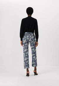 Pantaloni floral cu talie înaltă în nuanțe de albastru și alb, cu un design drept și un brâu contrastant. Asortați cu un top negru cu mânecă lungă și tocuri.