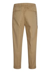 Beige casual pants with elastic waistband, two back welt pockets, rolled cuffs, and a silver chain attached to the right pocket.