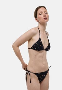 Ensemble de bikini noir comprenant un haut triangulaire et un bas à liens sur les côtés, orné de petits motifs floraux, fabriqué en tissu doux.