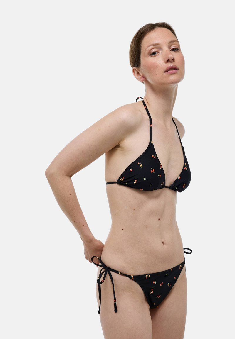 Ensemble de bikini noir comprenant un haut triangulaire et un bas à liens sur les côtés, orné de petits motifs floraux, fabriqué en tissu doux.