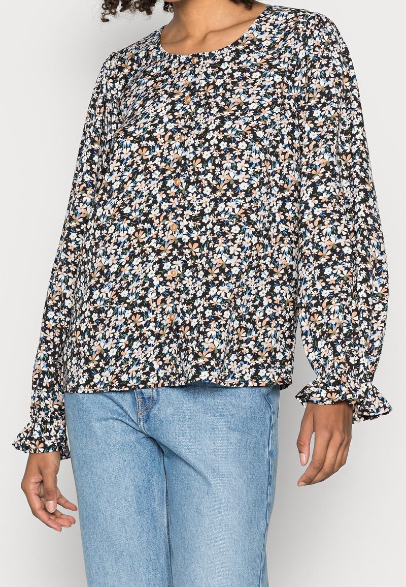 Svart blommig blus med långa, puffiga ärmar och rund halsringning. Har en mix av små blå och persikofärgade blommor på en mörk bakgrund.