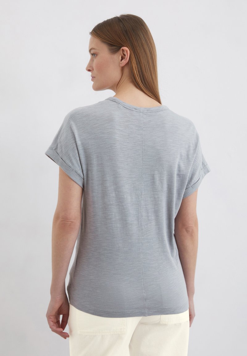 Graues Kurzarmshirt mit lockerer Passform, runder Halslinie und umgeschlagenen Ärmeln. Weicher Stoff mit dezenten Streifen und abgerundetem Saum.