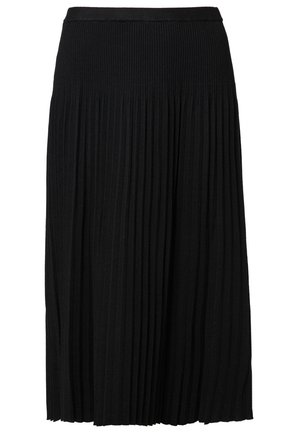 Kvinde iført en sort-hvid tjekket omslagstop, sort plisseret midi-nederdel, sorte strømpebukser og sort-hvide loafers går fremad.