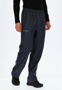 Waterdichte, donkergrijze broek met een elastische tailleband, zijzakken en "SWEDEMOUNT" branding op het linkerbeen. Glad textuur.
