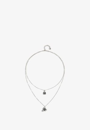 Collar de plata en capas con dos cadenas. Una cadena presenta un colgante cuadrado, mientras que la otra tiene un colgante redondo. Diseño simple, textura suave.