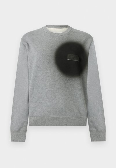 Hellgraues Sweatshirt mit Rundhalsausschnitt und langen Ärmeln, gerippten Bündchen und Saum sowie einem schwarzen runden Aufnäher auf der linken Brust mit einem kleinen Etikett.