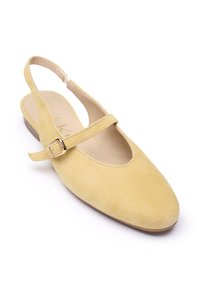 Sárga szarvasbőr pántos cipő lekerekített orral, lapos sarokkal és állítható pánttal, kis csat díszítéssel. Simított belső bélés.