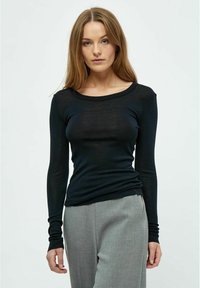 Schwarzes Langarmoberteil aus leichtem Material, mit rundem Ausschnitt und figurbetontem Schnitt, kombiniert mit hellgrauen Hosen.