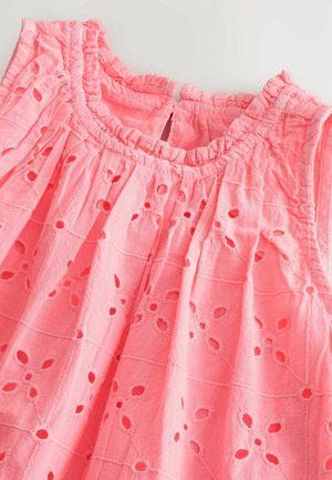 Vaaleanpunainen puuvillatunika, jossa on brodeerattuja kukkaleikkeitä, röyhelökaulus ja rento istuvuus. Teksturoitu kangas lisää visuaalista kiinnostavuutta.