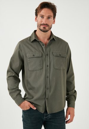 Olivgrünes Button-up-Hemd mit zwei Brusttaschen, langen Ärmeln und einer lockeren Passform, aus leichtem Stoff mit glatter Textur.
