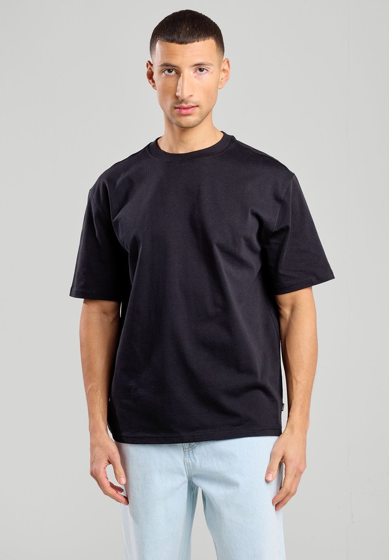 T-shirt nera a maniche corte realizzata in cotone, con scollatura a girocollo e vestibilità comoda. Tessuto texturizzato con una finitura liscia.