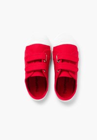 Zapatos de lona rojos con suelas de goma blanca, que presentan dos correas de velcro y letras de marca en el interior. Textura suave con diseño de punta redonda.