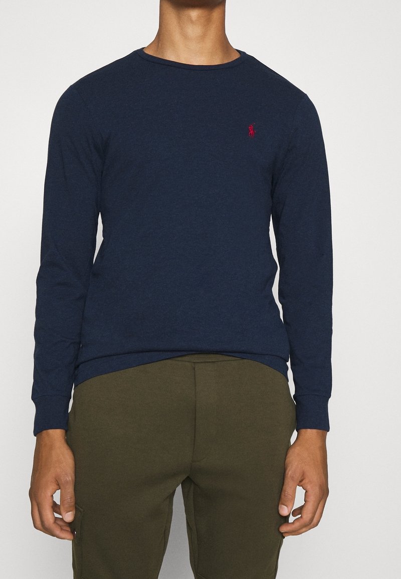 Mörkblå långärmad T-shirt i bomull med rund halsringning och en liten röd logotyp på bröstet. Mjuk textur och figursydd design.