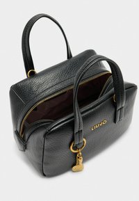 Sac à main en simili cuir noir avec double anses, quincaillerie dorée, fermeture éclair et logo de marque. Intérieur doublé d'un bordeaux profond.