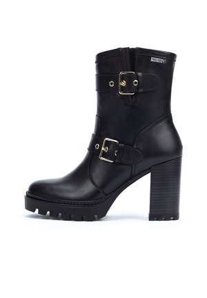 Black leather ankle boots with a chunky high heel, featuring two adjustable straps with golden buckles and a textured rubber sole.