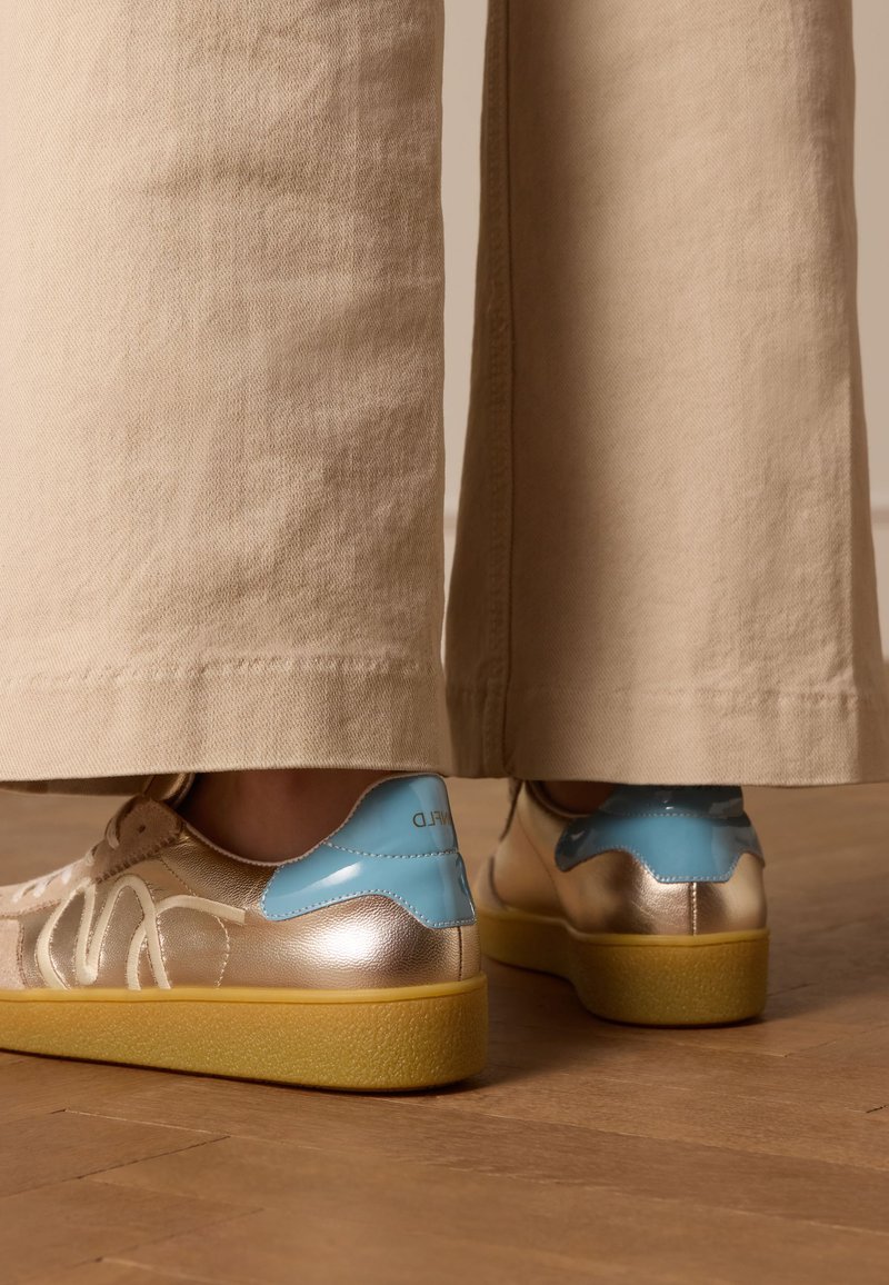 Gouden en blauwe sneakers met een gestructureerde, gele zool. Heeft een gladde metallic afwerking en ingewikkelde ontwerpdetails aan de zijkanten.