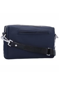 Borsa a tracolla in nylon blu navy con zip argentata, tracolla nera rimovibile e tasca posteriore a scomparsa. Presenta una texture liscia e un design elegante.