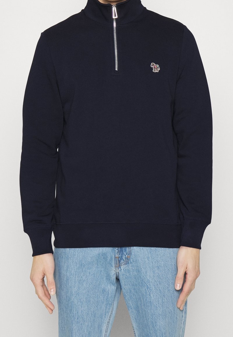 Felpa navy a maniche lunghe con colletto alto, zip frontale a metà e un piccolo logo ricamato sul petto; realizzata in tessuto morbido.