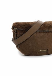 Sac en fausse fourrure brun avec une sangle en cuir lisse et une fermeture à glissière. Il présente une forme arrondie et un discret logo sur le devant.