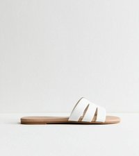 Sandalias de slide blancas con tres correas anchas y un acabado suave. La suela es marrón, plana y ligeramente texturizada para proporcionar agarre.