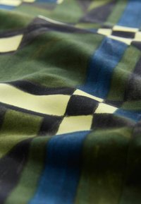 Nyomtatott szövet, zöld, kék, sárga és fekete sakktáblaszerű mintával. Simább felület, változatos árnyalatokkal és enyhe fénylással.