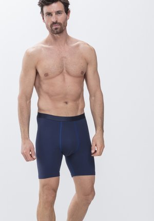 Caleçons de bain bleu marine en tissu extensible avec une ceinture noire lisse. Présente des coutures contrastantes bleu le long des coutures.