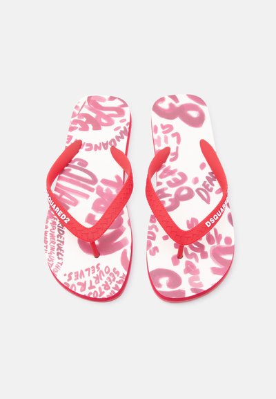 Tongs blanches avec des brides rouges, texte style graffiti rouge imprimé sur les semelles et marque "DSQUARED2" sur les brides.