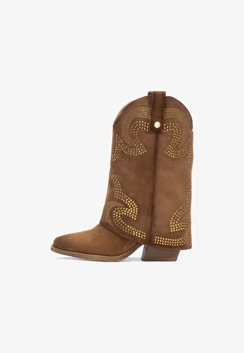 Bota de cowboy de ante marrón con puntera afilada, decorada con tachuelas doradas en un patrón en espiral, y un tacón bajo apilado.