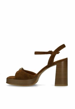 Bruine suède sandaal met hoge hak en blokhak, open teen, enkelbandje en plateauzool, zijaanzicht op witte achtergrond.