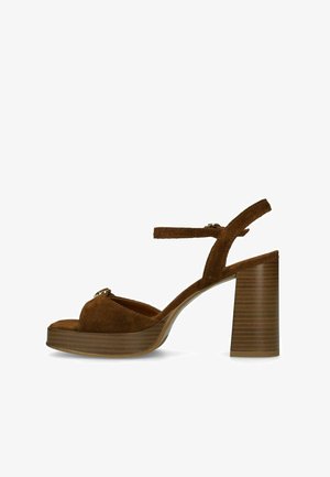 Bruine suède sandaal met hoge hak en blokhak, open teen, enkelbandje en plateauzool, zijaanzicht op witte achtergrond.