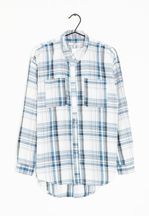 Koszula na długi rękaw z guzikiem, o wzorze w kratę w kolorach niebieskim, szarym i białym, z dwiema kieszeniami na piersi, wisząca na czarnym wieszaku.