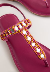 Sandales en cuir violet avec bride en T décorées de perles roses, jaunes et d'embellissements hexagonaux argentés réfléchissants.