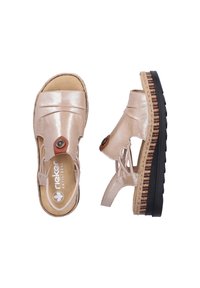 Sandales en cuir beige à bout ouvert avec des brides élastiques sur les côtés, un bouton décoratif, et une semelle plateforme épaisse en noir et liège, vues de dessus et de côté.