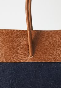 Brown leather top and handles with textured finish, paired with navy fabric lower section. Straight-edged design, minimal stitching detail.