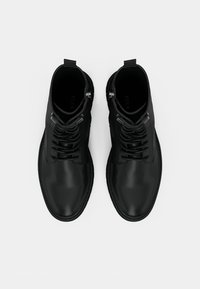 Crne gležnjače od glatke kože, s vezicama i srebrnim detaljima te petljom za lako navlačenje na stražnjoj strani.