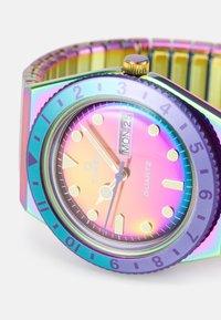 Colorful quartz watch with a rainbow metallic case, round face, and a gradient dial featuring gold hour markers and hands. Adjustable link band.