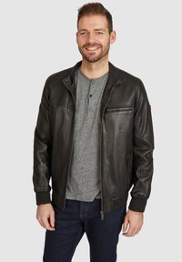 Čierna kožená bomber bunda s rebrovými manžetami, golierom a zipsovým predným vreckom. Nosená cez šedú henley košelu a tmavé džínsy.