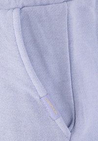 Ljusblå sweatshirttyg med en sidoficka och en guld logotags. Mjuk textur och sportig design med en avslappnad passform.