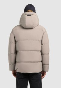 Light beige puffer jacket with a hood, featuring wide horizontal quilted sections and a small logo on the back. Black accents on the cuffs.