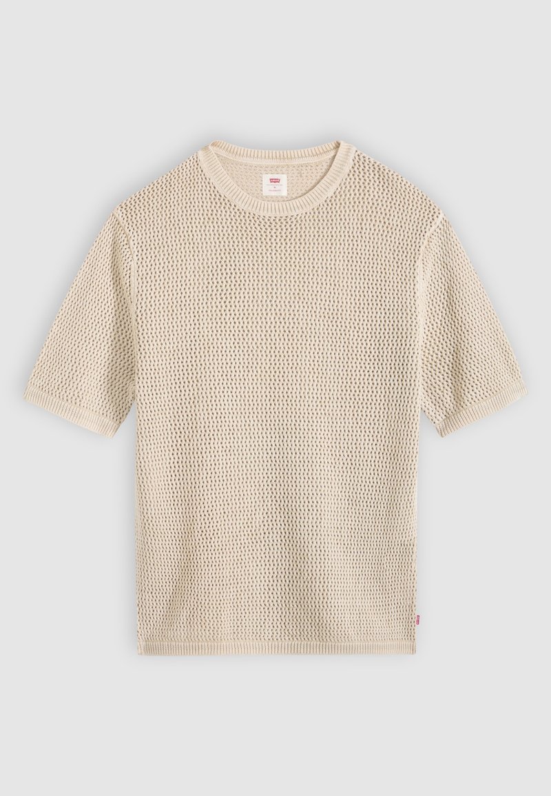 Pull en maille beige à manches courtes avec un col rond et un motif en maille ajourée texturé, posé à plat sur un fond clair.