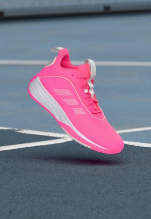 Jasnoróżowy but sportowy z siatkową cholewką, ozdobiony trzema białymi paskami, z teksturowaną podeszwą i sznurowadłami w dopasowanym kolorze różowym. Emanuje aktywnym designem.