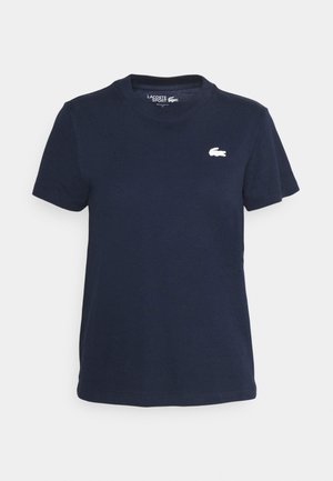 Marineblå bomulls t-skjorte med rund hals og korte ermer. Har en liten hvit Lacoste-logo på venstre bryst. Myk tekstur.
