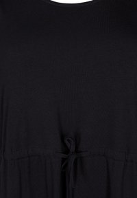 Haut noir en tissu doux, avec un col rond, une taille froncée avec un lien, et une coupe ample. Design minimaliste, sans motifs.