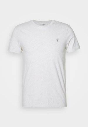 Lys grå bomull t-skjorte med rund hals og korte ermer. Har en liten brodert logo på venstre bryst. Myk tekstur.