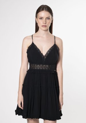 Robe noire avec bretelles spaghetti, un décolleté orné de dentelle, des volants superposés et une taille ajustée en dentelle. Texture de tissu lisse.