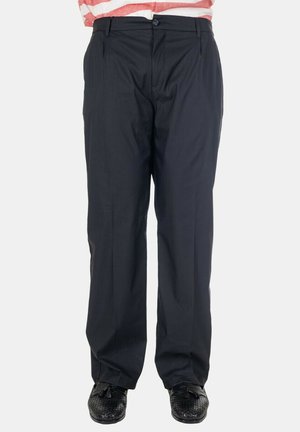 Pantaloni neri da uomo a gamba dritta abbinati a mocassini neri intrecciati con nappine e camicia a righe rosse e bianche infilata dentro.
