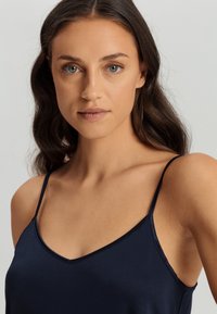 Camisola in satin blu navy con spalline sottili, caratterizzata da una scollatura a V e una texture liscia. Design semplice senza motivi o accenti visibili.