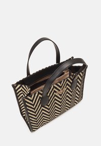 Sort og beige håndtaske med fiskebensmønster, to sorte håndtag, guld logo og en lynlåslomme indeni.
