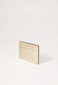 Cardholder din piele aurie cu suprafață texturată, având două sloturi pentru carduri, margini cusute și o formă rectangulară subțire.