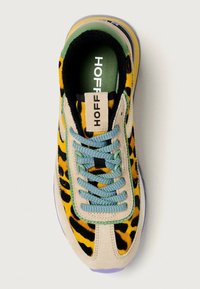 Baskets multicolores présentant un motif léopard jaune et noir, avec une base en daim beige, des accents verts et des lacets bleus.